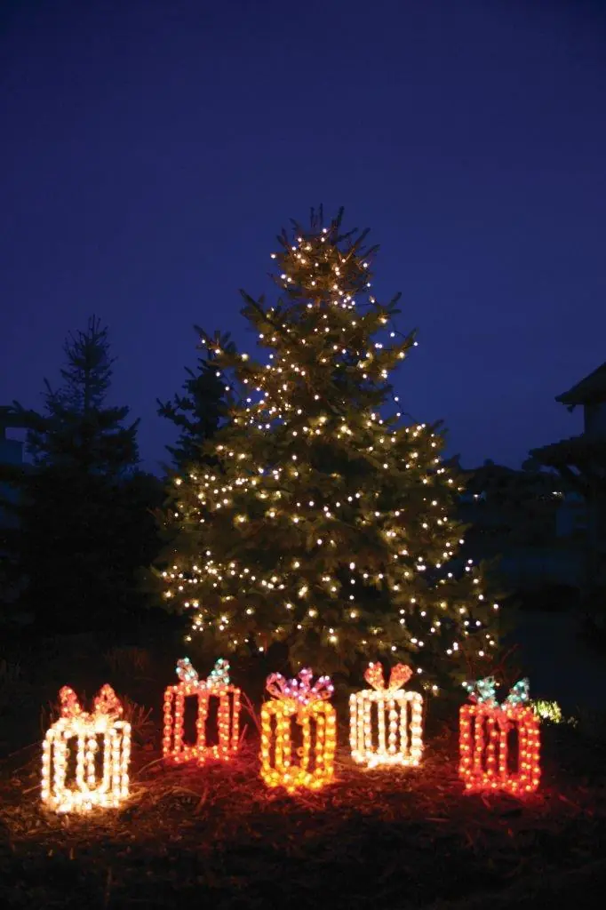 Holiday lighting display with an outdoor tree and illuminated gift boxes