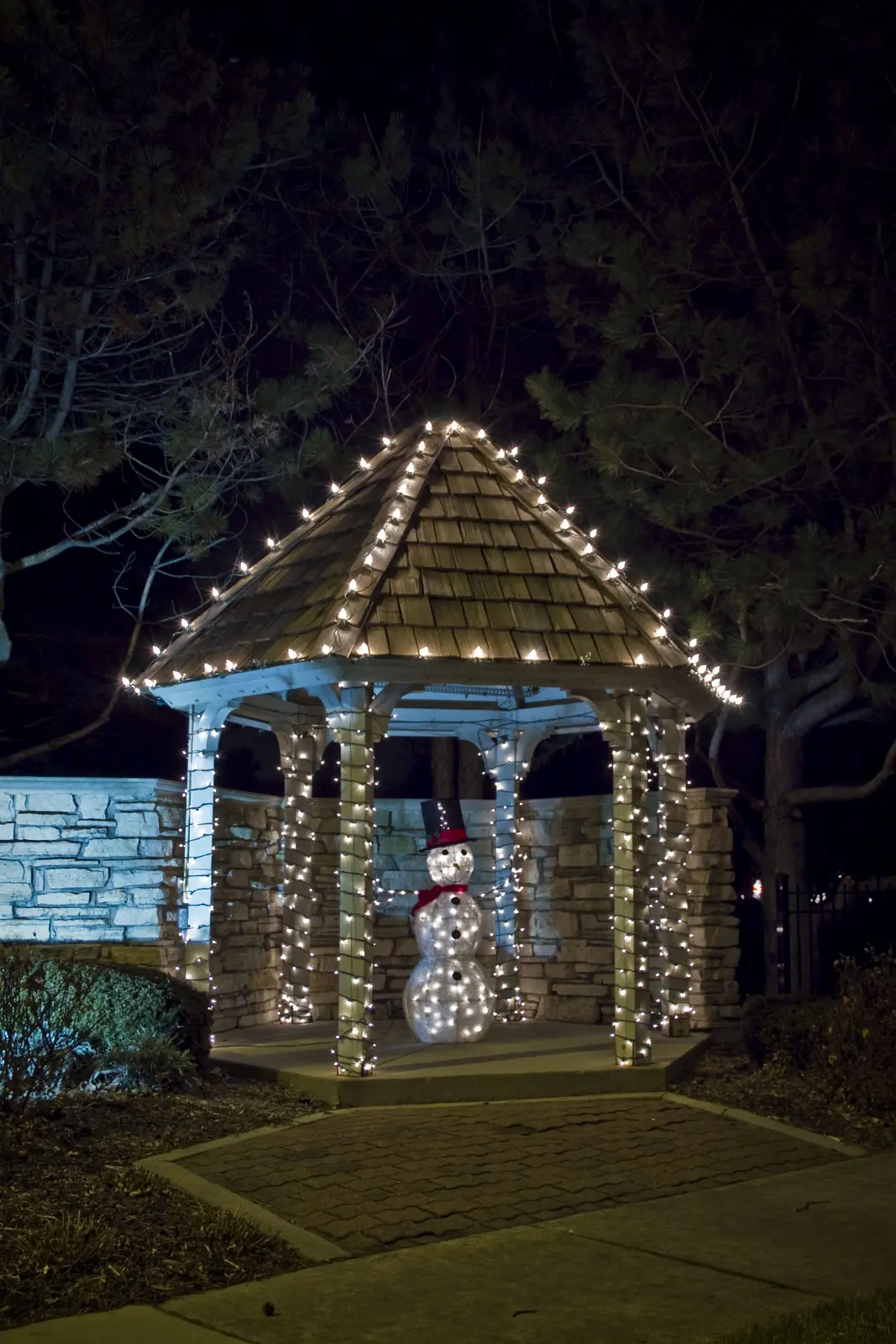 Gazebo wrapped in white bulbs with an illuminated wreath and snowman
