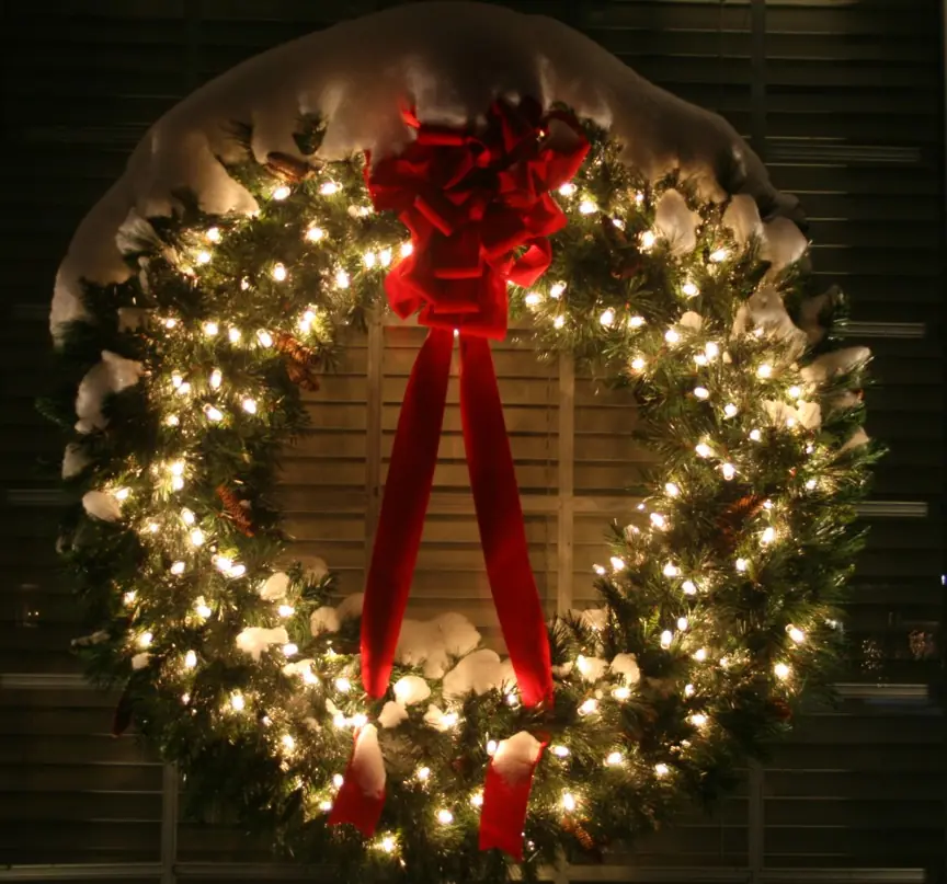 Illuminated holiday wreath finished with a large red Christmas bow