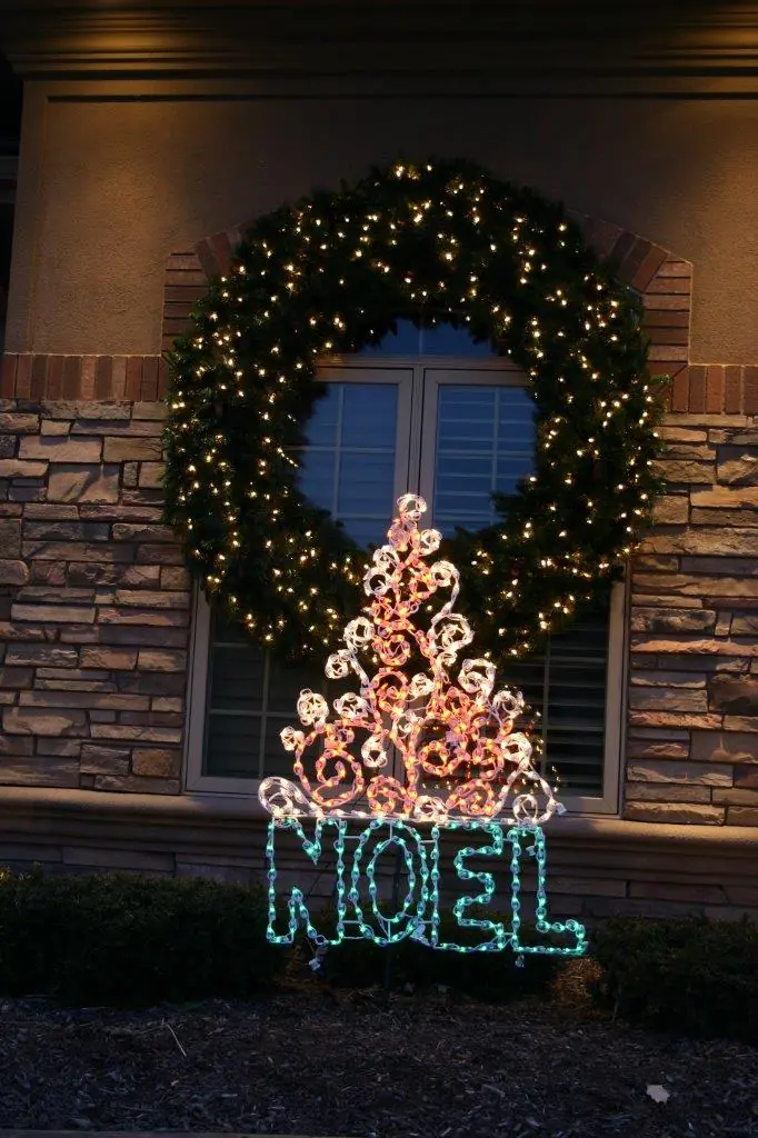 NOEL holiday lighting display beneath a decorated window wreath