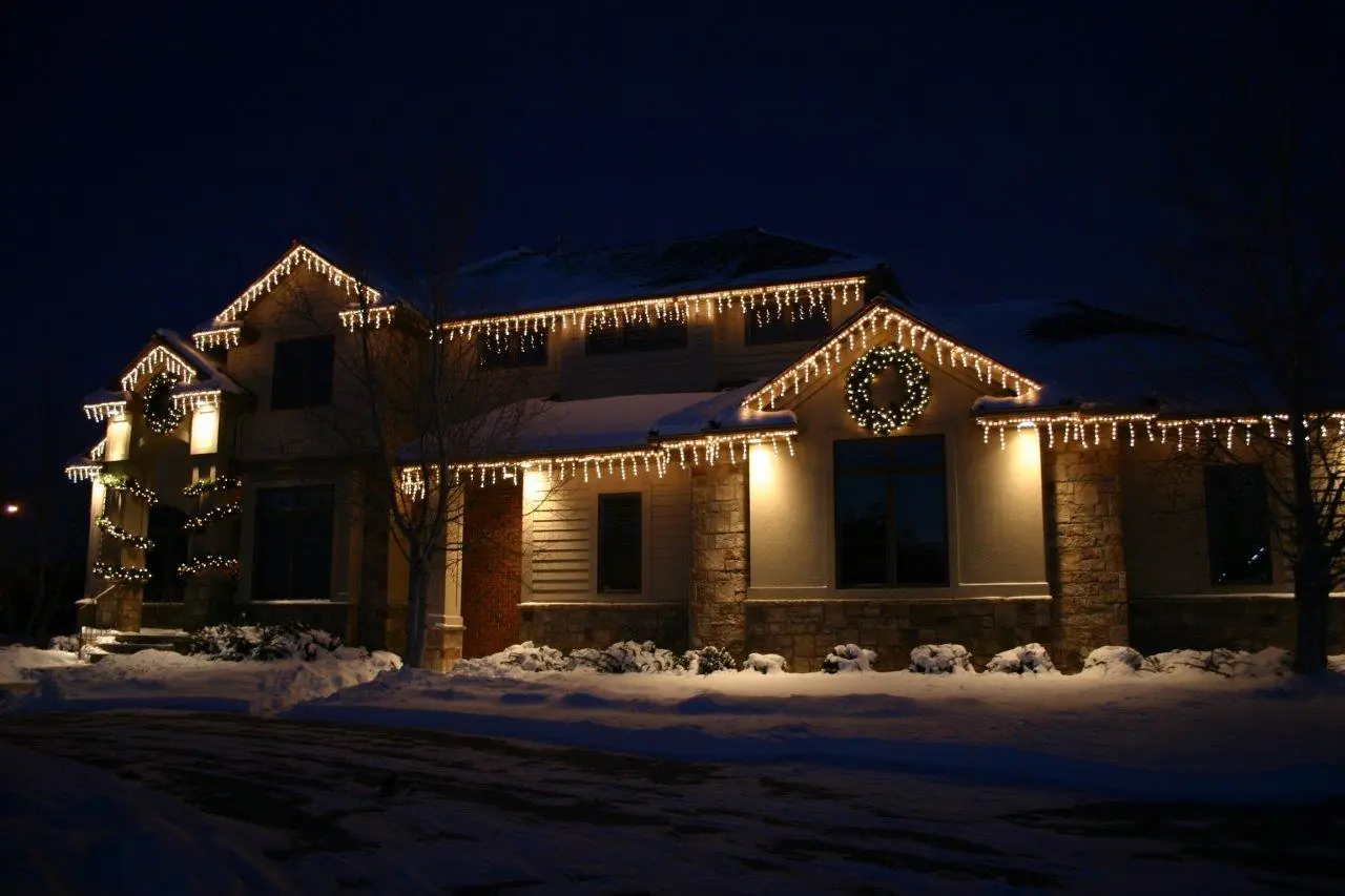 Snowy home decorated with icicle lights, wreath, and garland