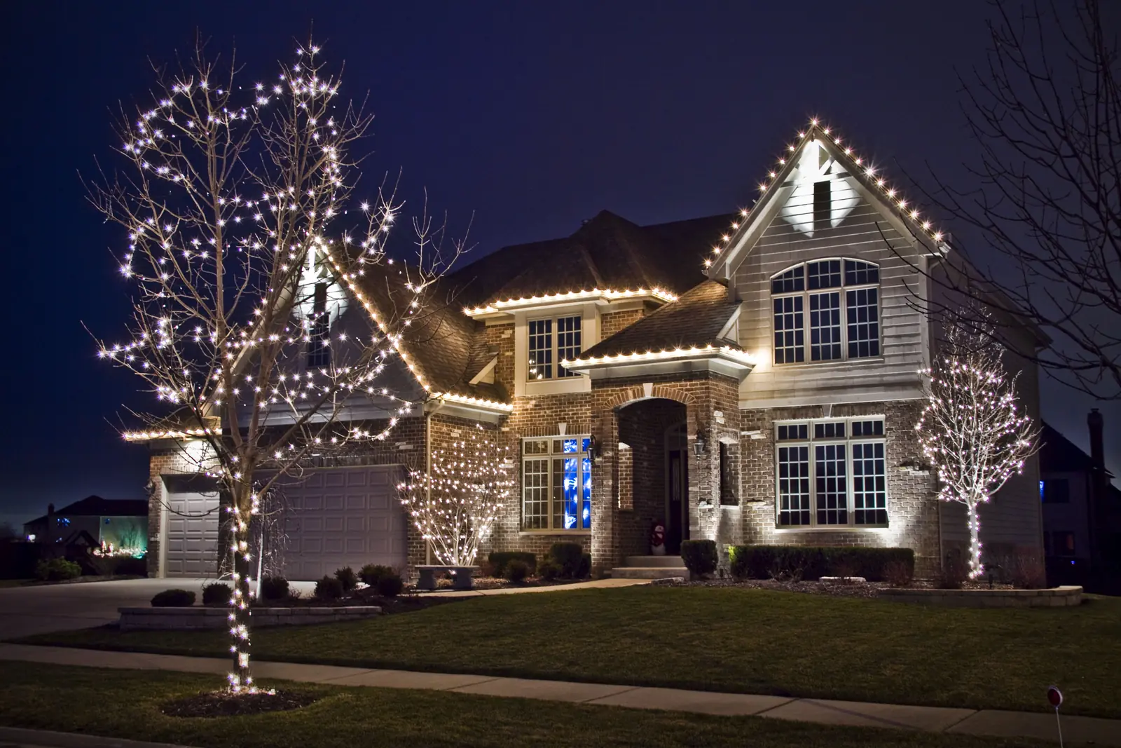 Residential lighting across rooflines and trees with coordinated colors